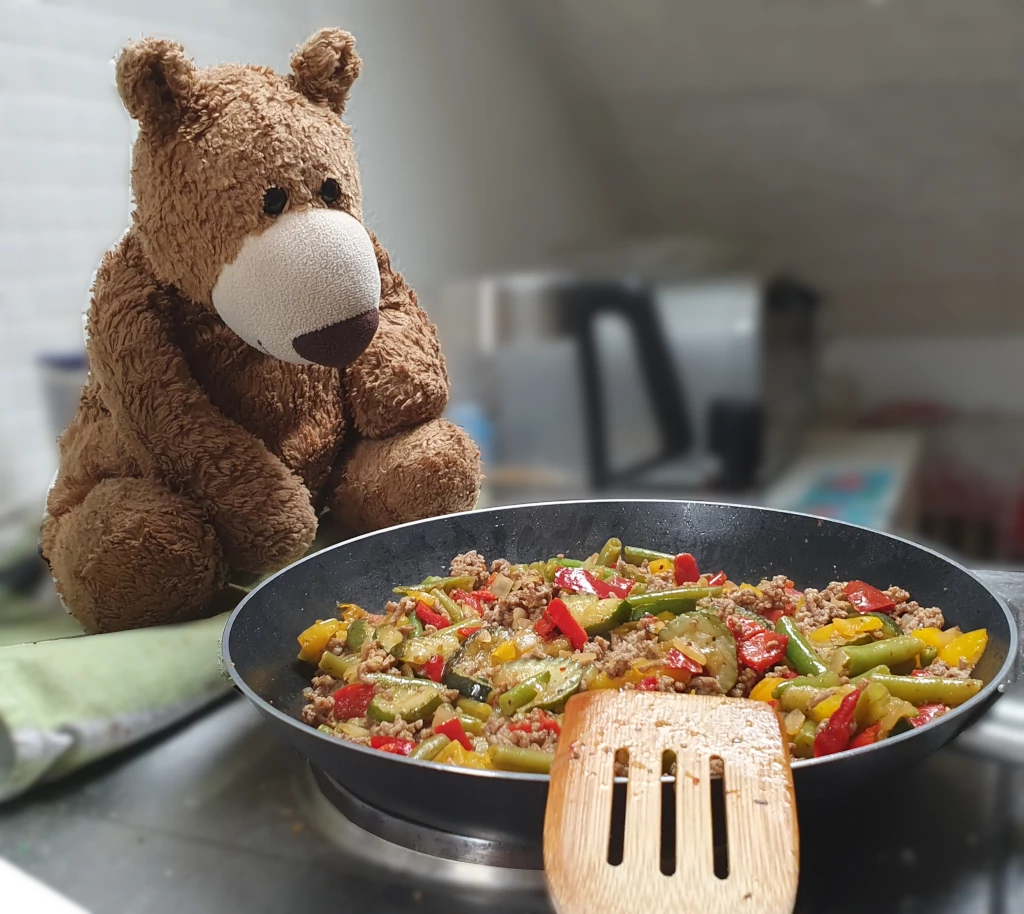 Der Bär schaut beim Kochen zu.